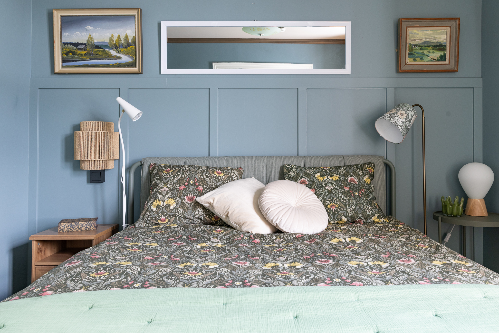Säng med blommiga kuddar och sänglampor