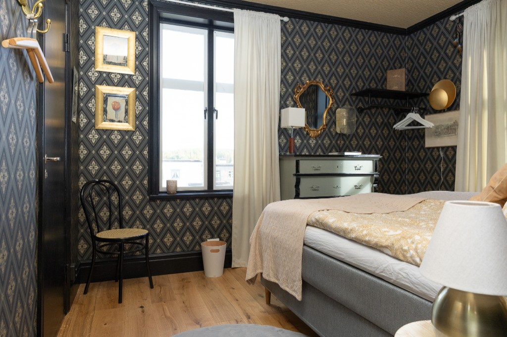 Hotellrum med mörk tapet och guldram